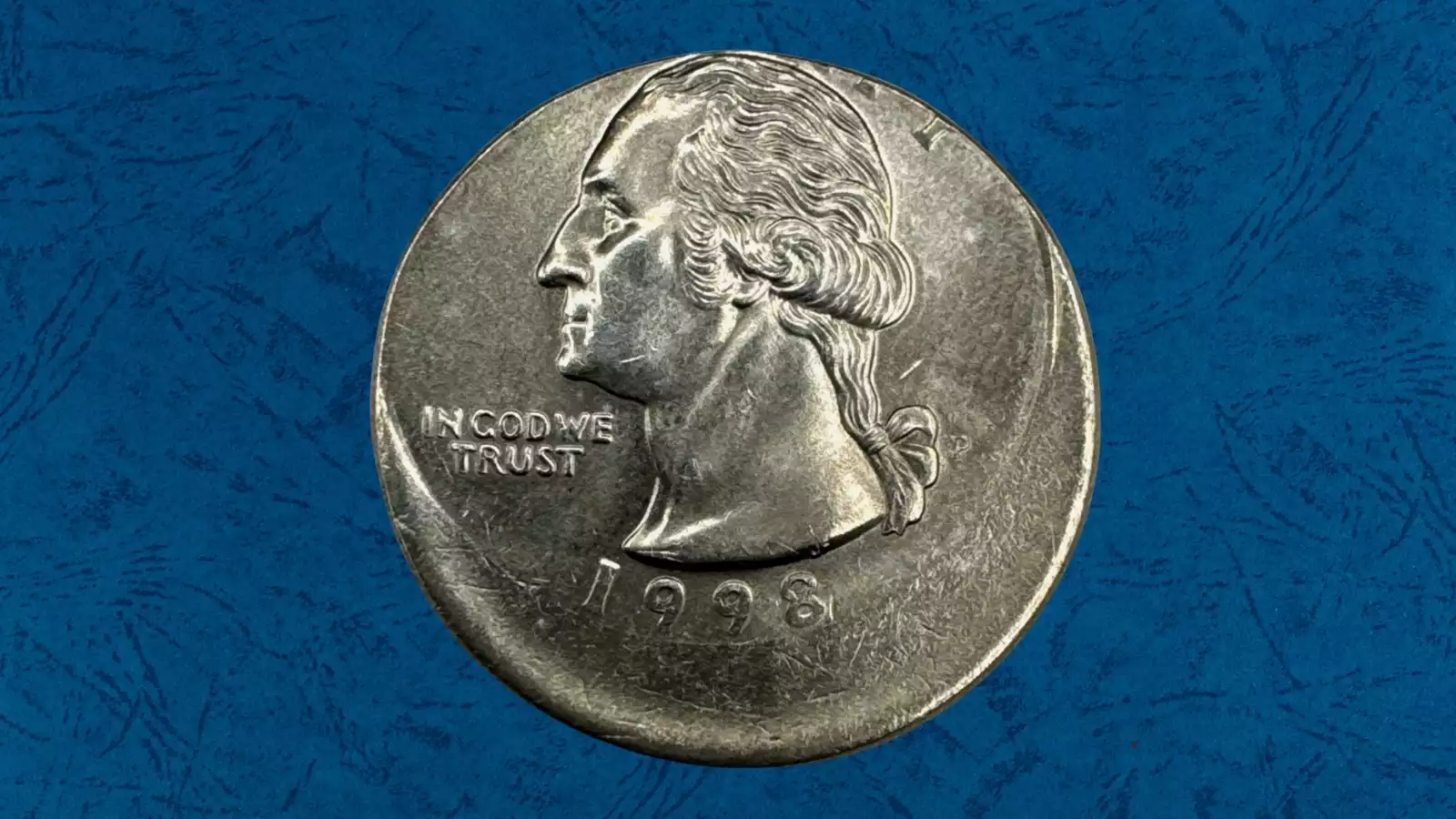 1998-P quarter off-center strike error showing design shifted approximately 50% from center with blank planchet crescent and visible date